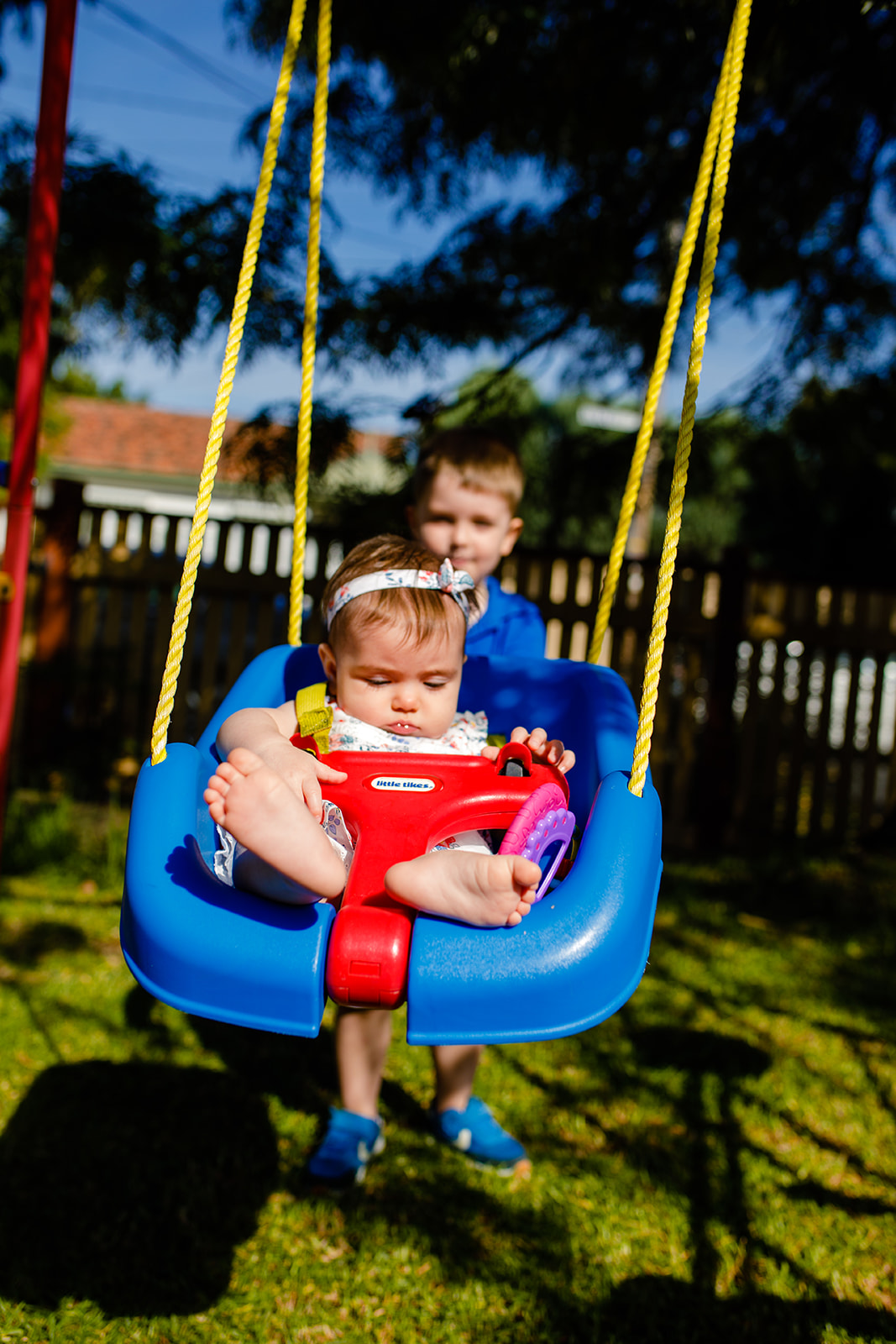 big brother pushing little sister on swing