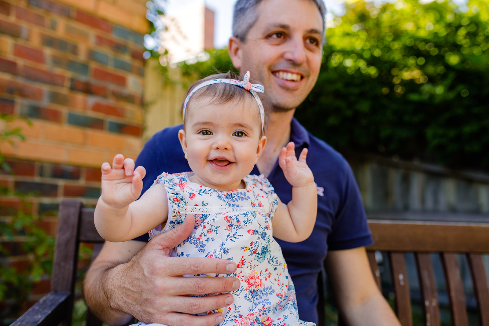 father holds his baby while she laughs at the photgrapher