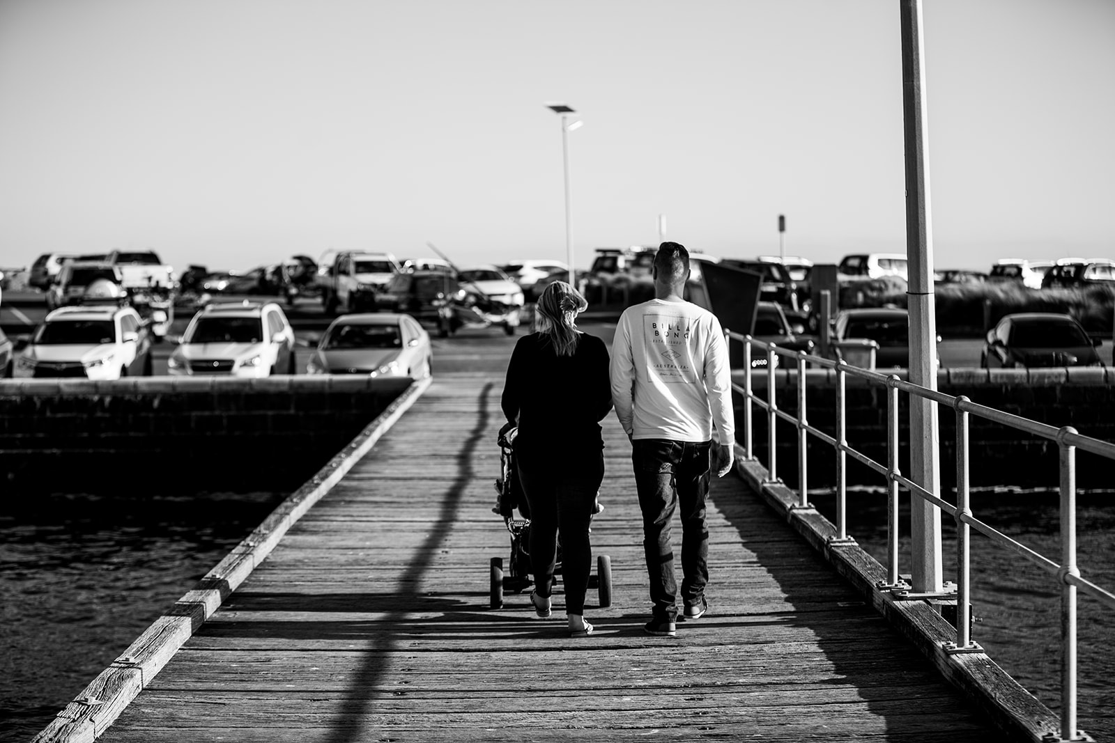 parents pushing a pram along the pier