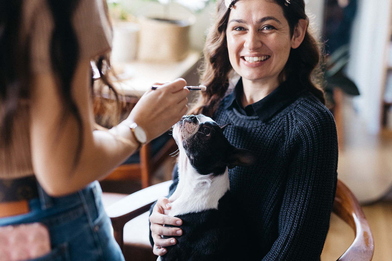 woman getting makeup done for her wedding day with a dog on her lap 