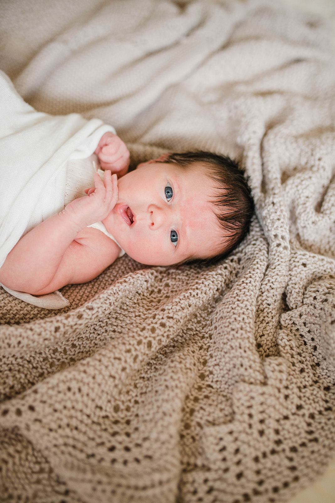 Photograph of newborn baby wraped and laying on a bed 