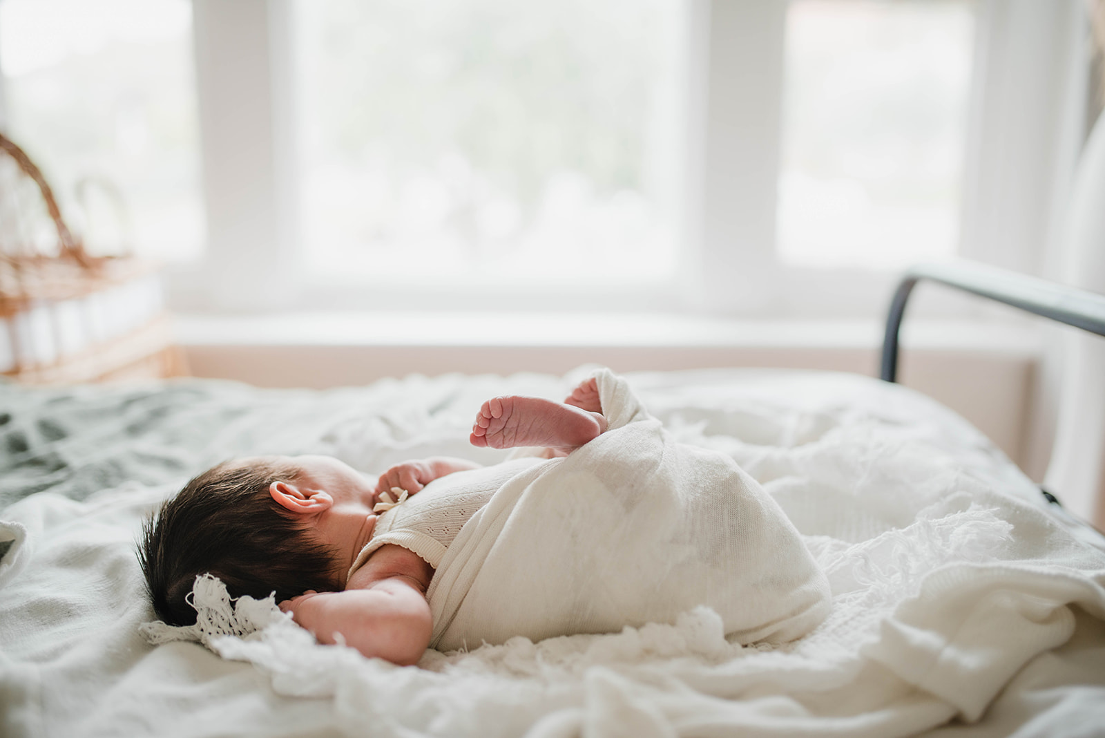 Photograph of newborn baby on a bed with soft window light 