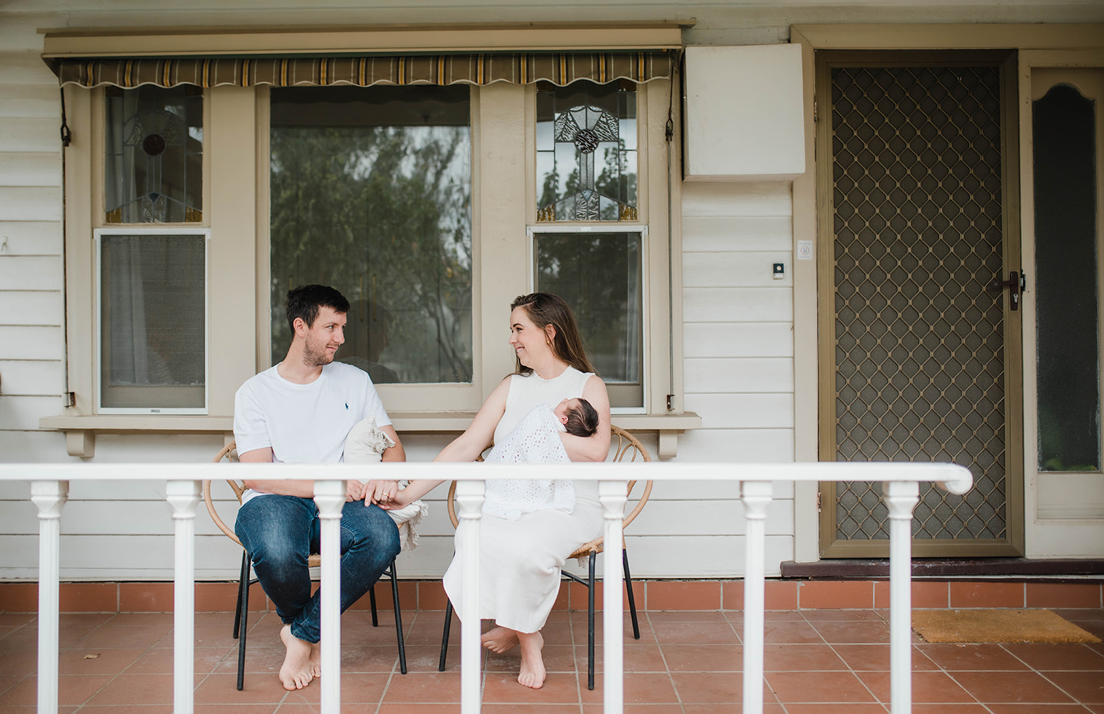Newborn family portrait of parents and baby on front porch 