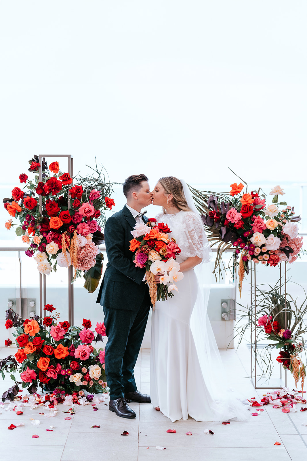 Same sex wedding photo two brides kissing amongst beautiful colourful flowers