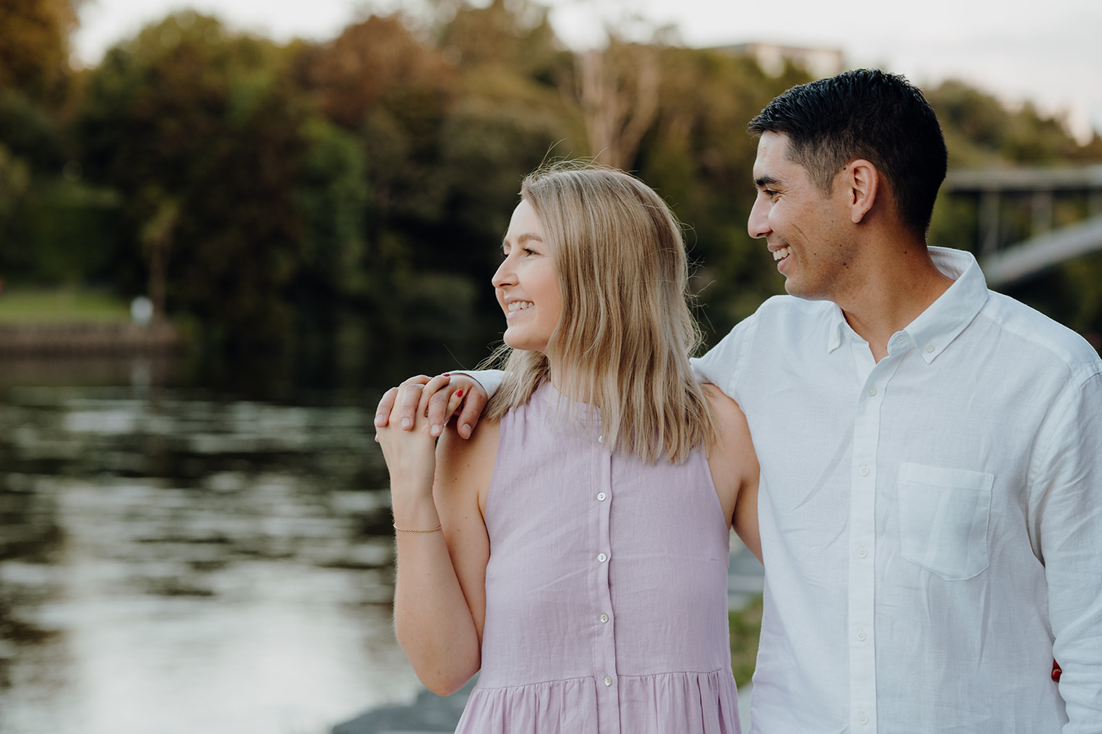 A couple holding hands in front of the waikato river during an engagement shoot with haley adele photography