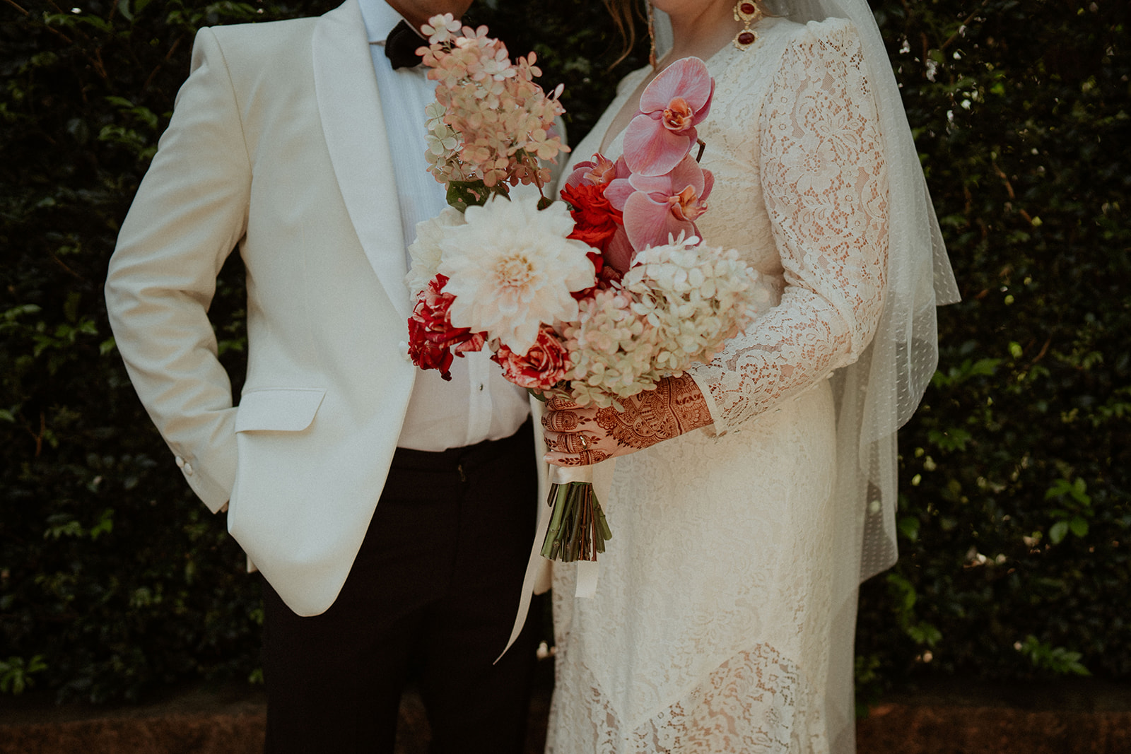 Bride and groom, standing together with a beautiful bouquet between them