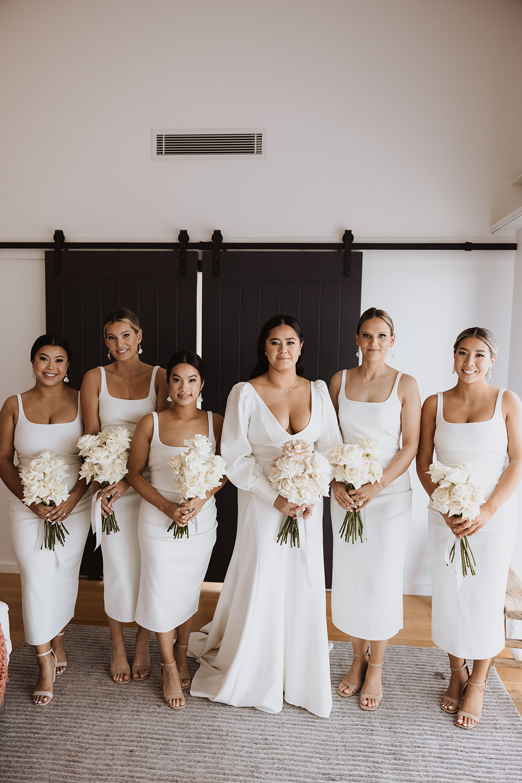 Bride with her bridesmaids wearing gown and holding flower bouquet