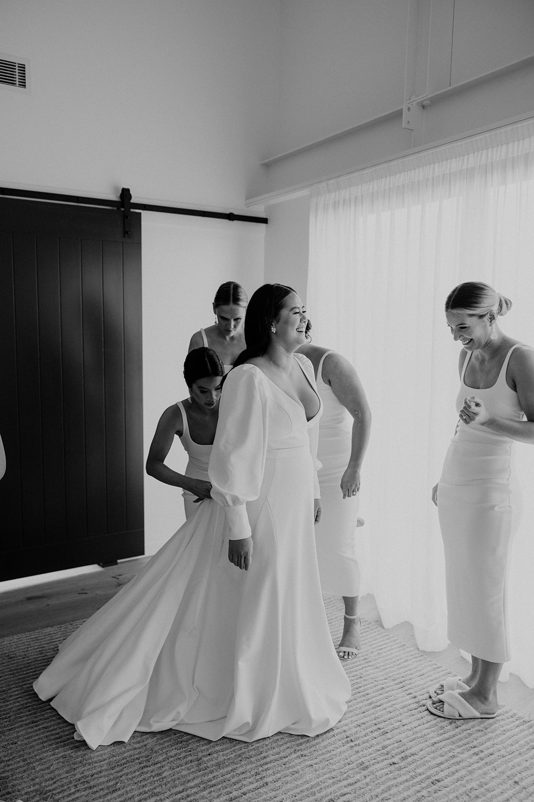 Bridesmaids helping the bride with her gown