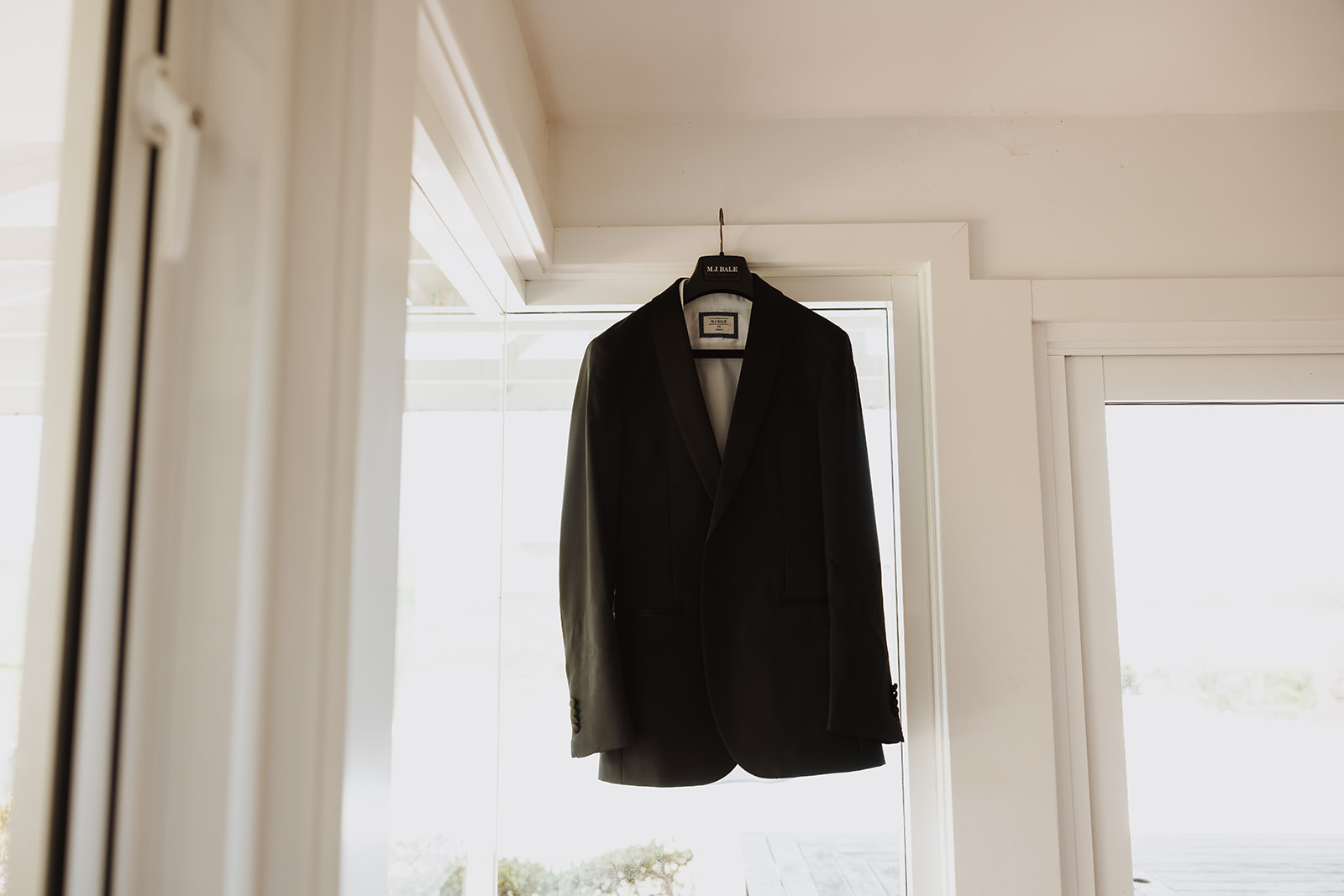Groom's black suit hanging on a white door