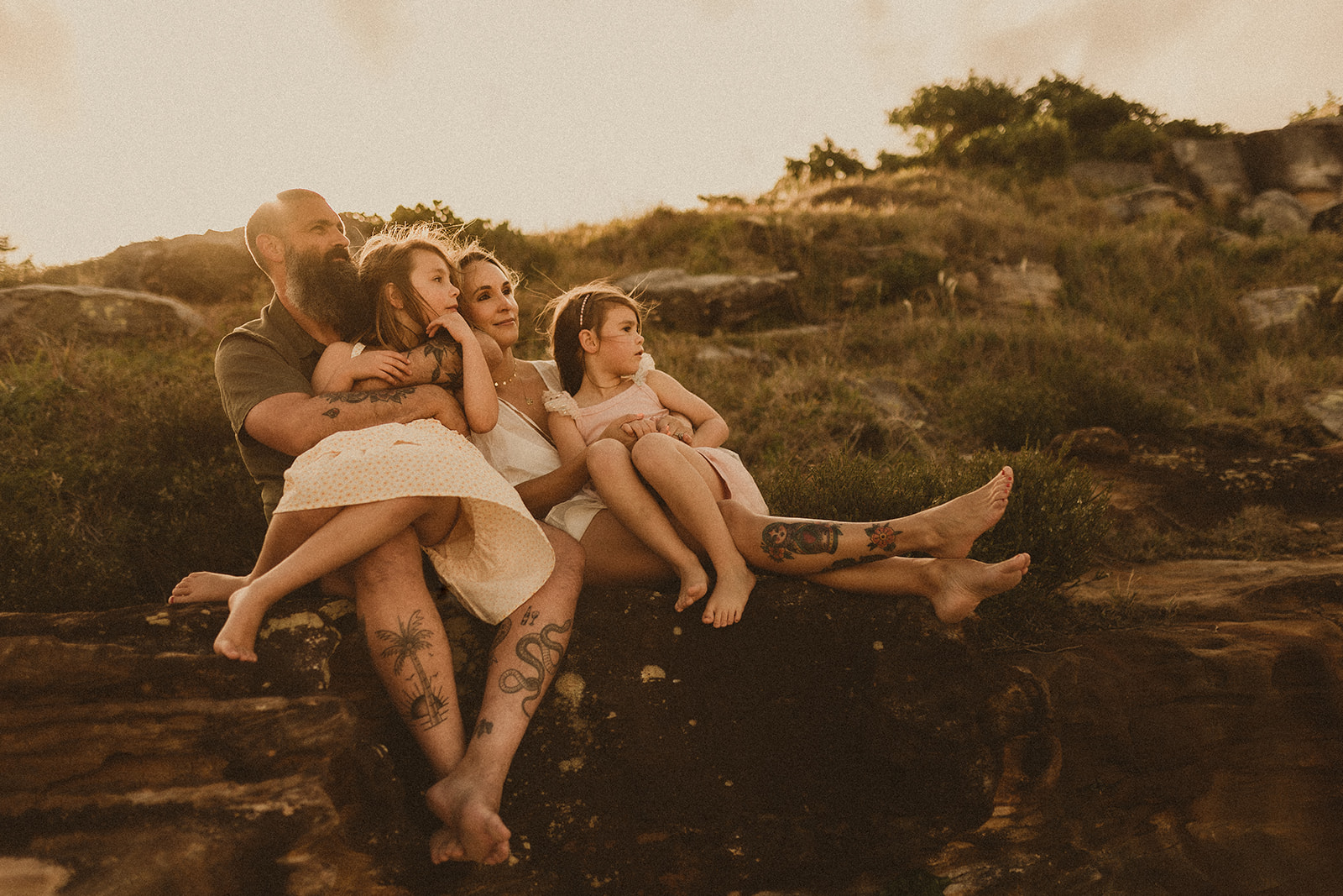 Family cuddling on the rocks, lots of legs everywhere. Family photographer Sydney
