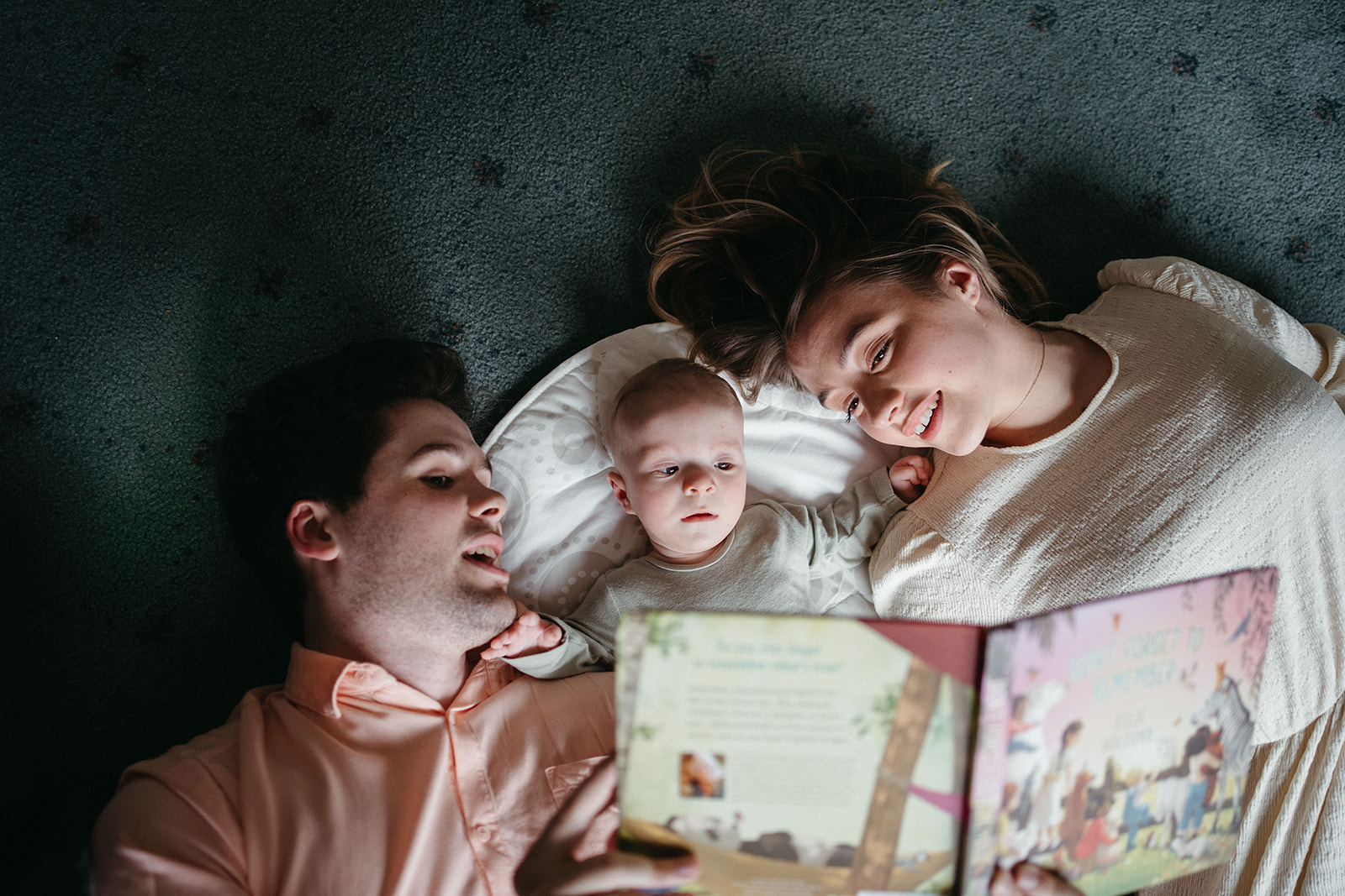 parents lie on the floor and read to their baby