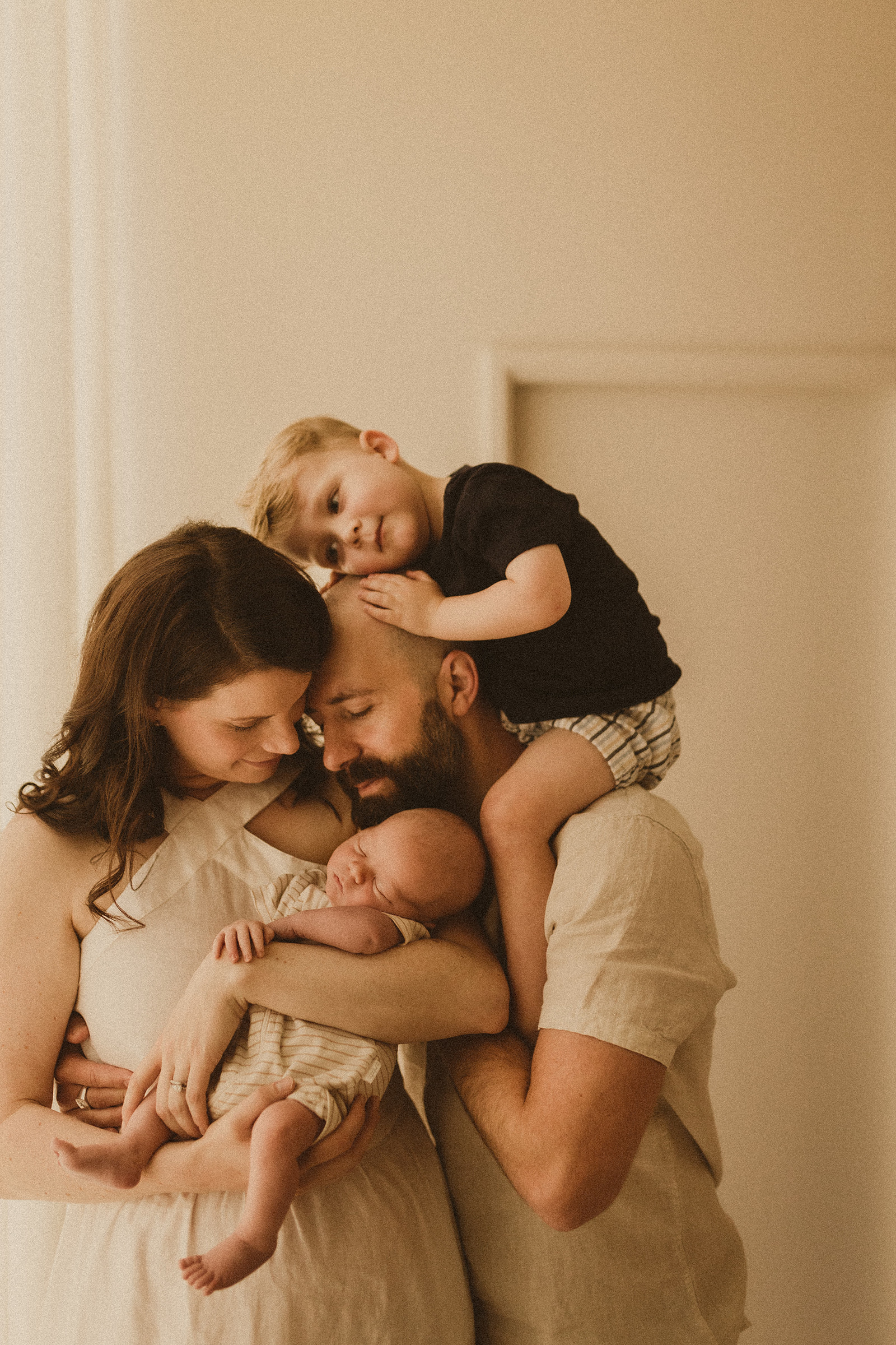 Newborn family photography Sydney. Family cuddle newborn, toddler on dads shoulders