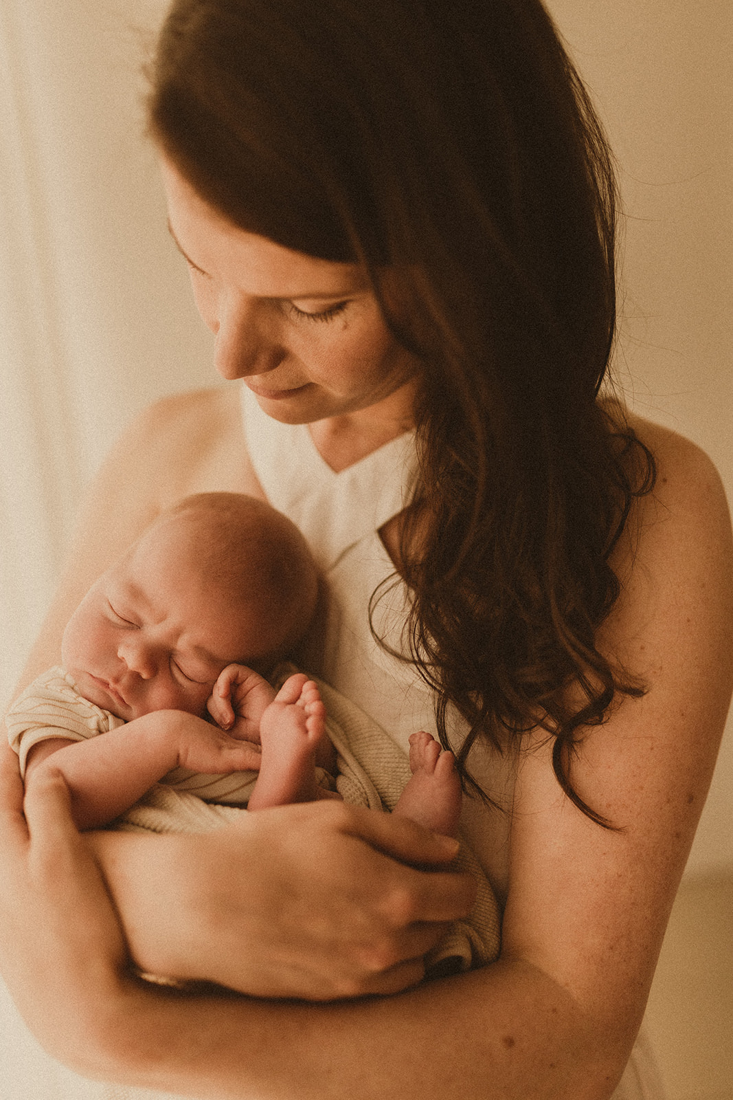 Newborn motherhood Photography Sydney. Mum holds newborn baby and looks at him with love.