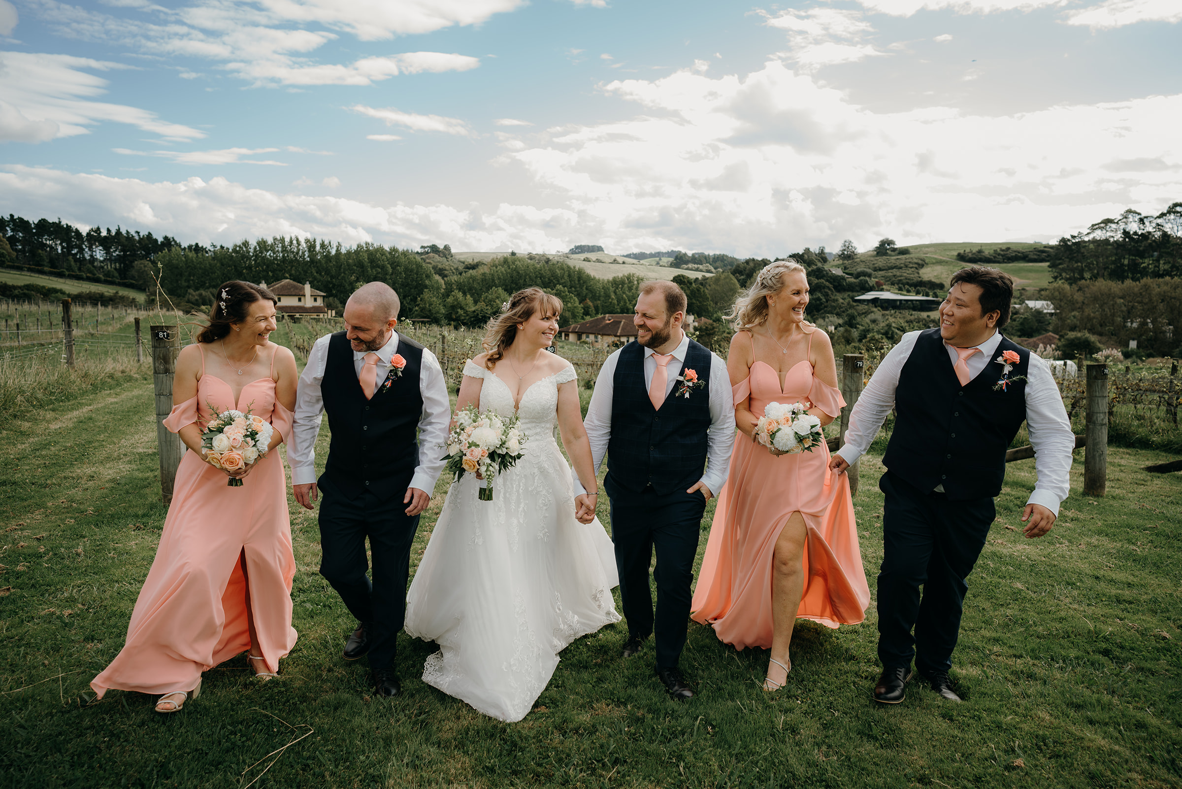 a couple a Turanga creek wedding venue in clevedon walk towards the camera with their bridal party 