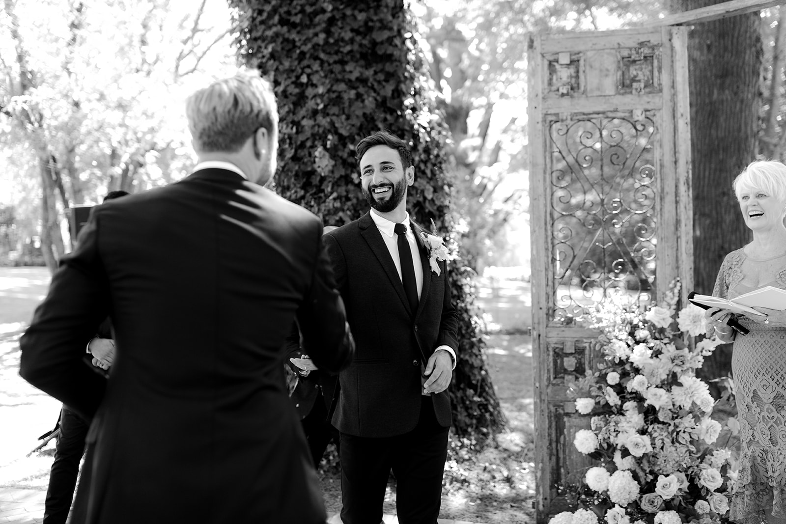 Groom welcoming floral man at the end of the aisle at an elegant country wedding.