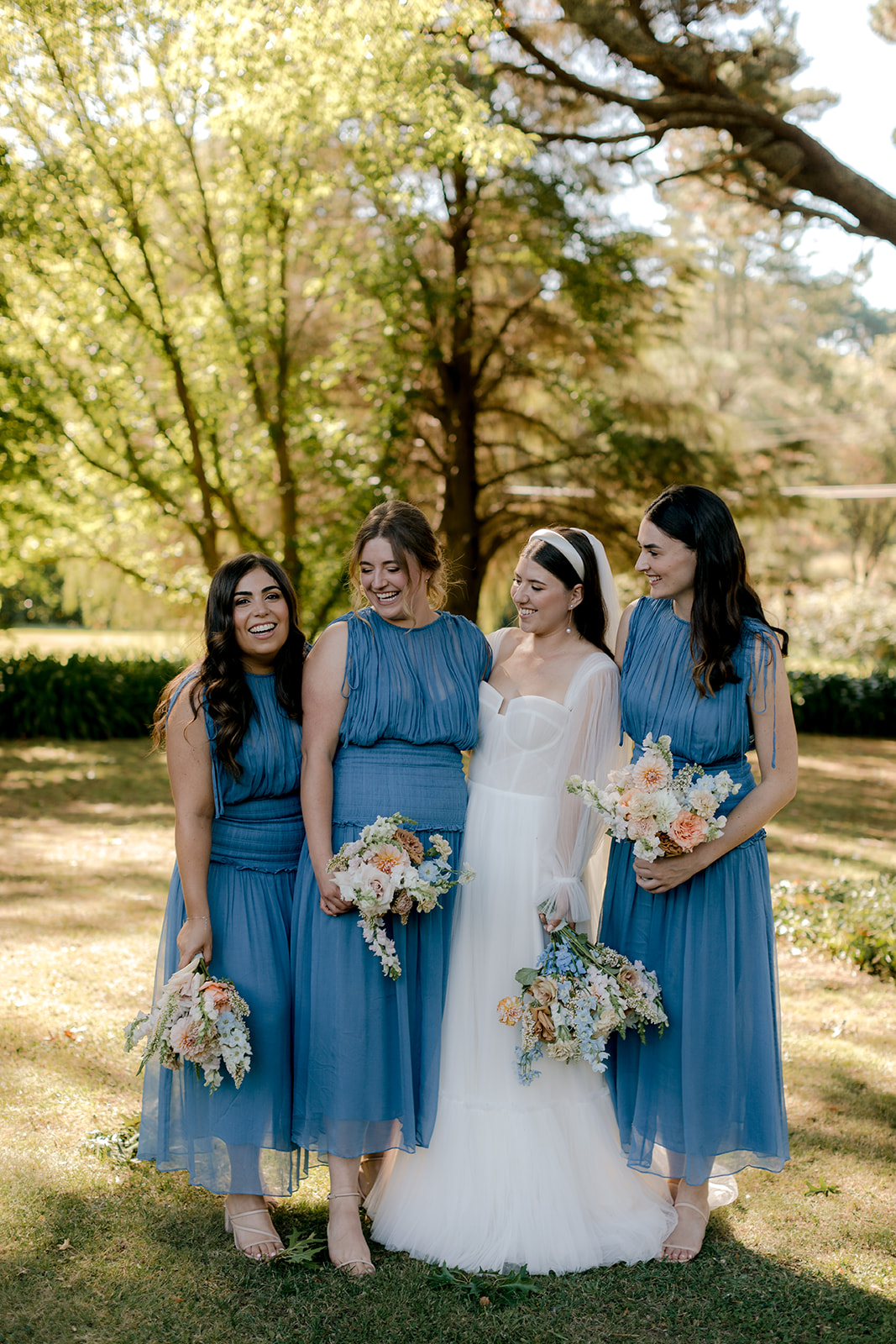 Bride with her bridesmaids holding their bridal bouquets at her elegant country wedding.