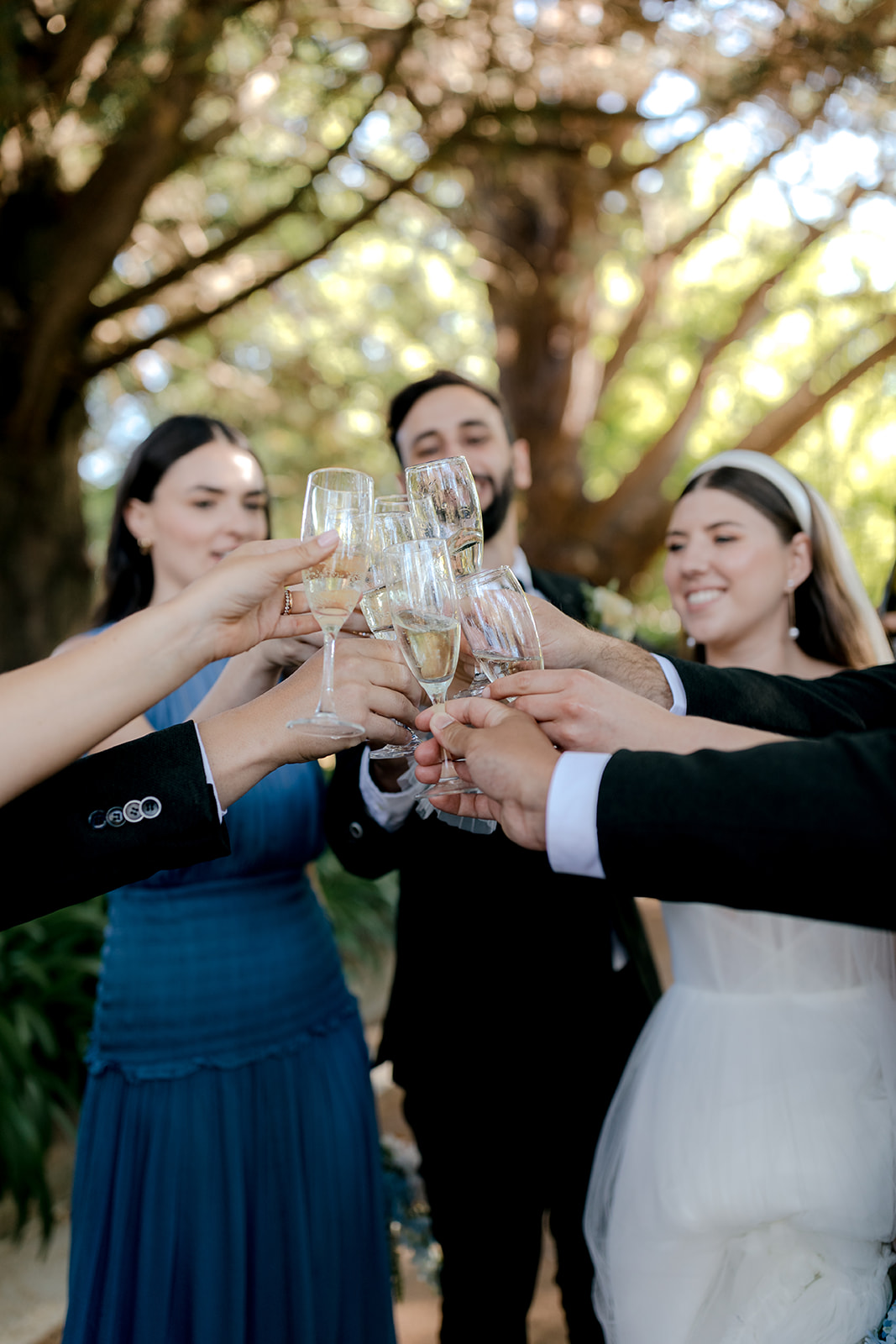 Bride & groom popping champagne with their wedding party during their elegant country wedding.