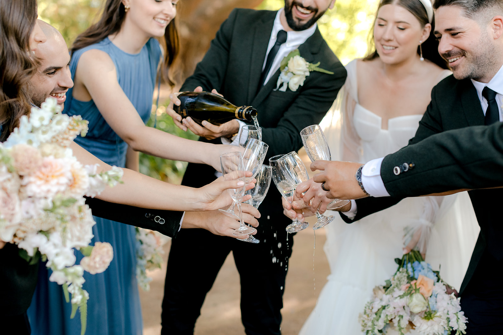Bride & groom popping champagne with their wedding party during their elegant country wedding.