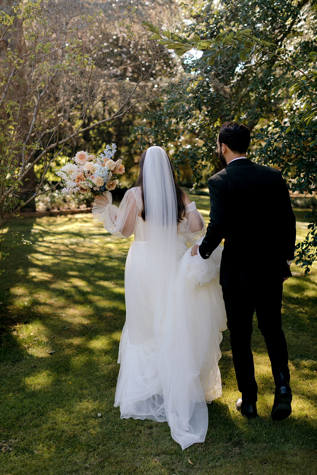 Bride & groom walking in an orchard during their elegant country intimate wedding.