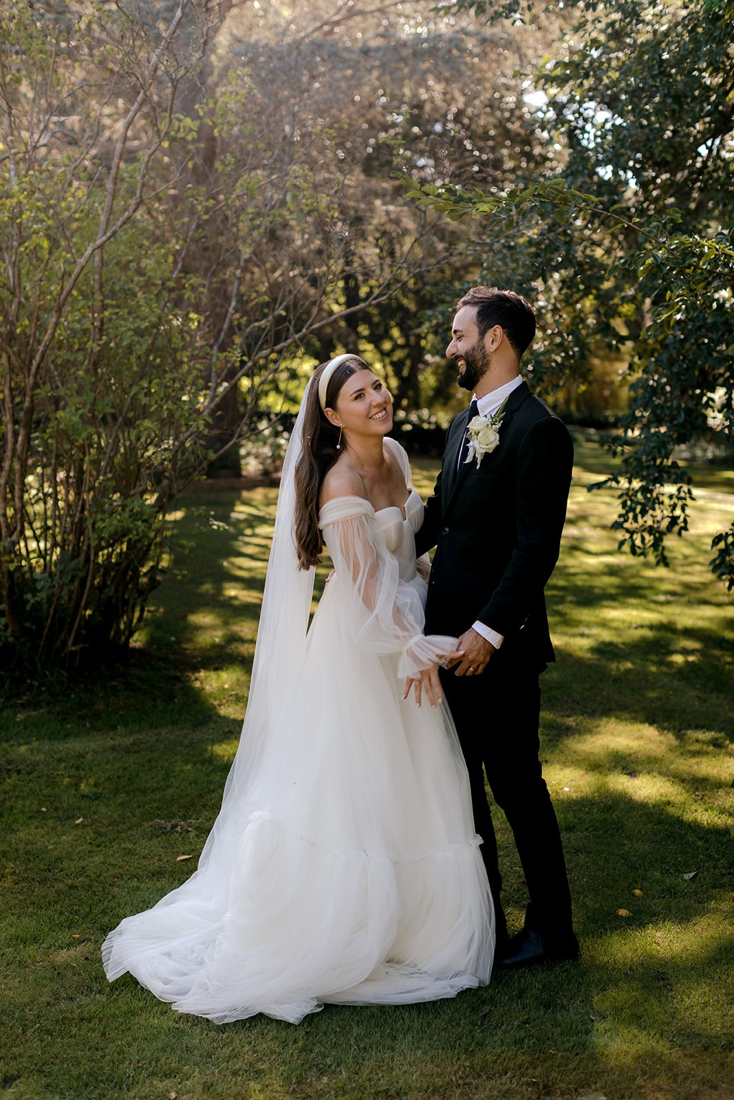 Portrait of bride & groom laughing in an English-inspired garden during their elegant country wedding.