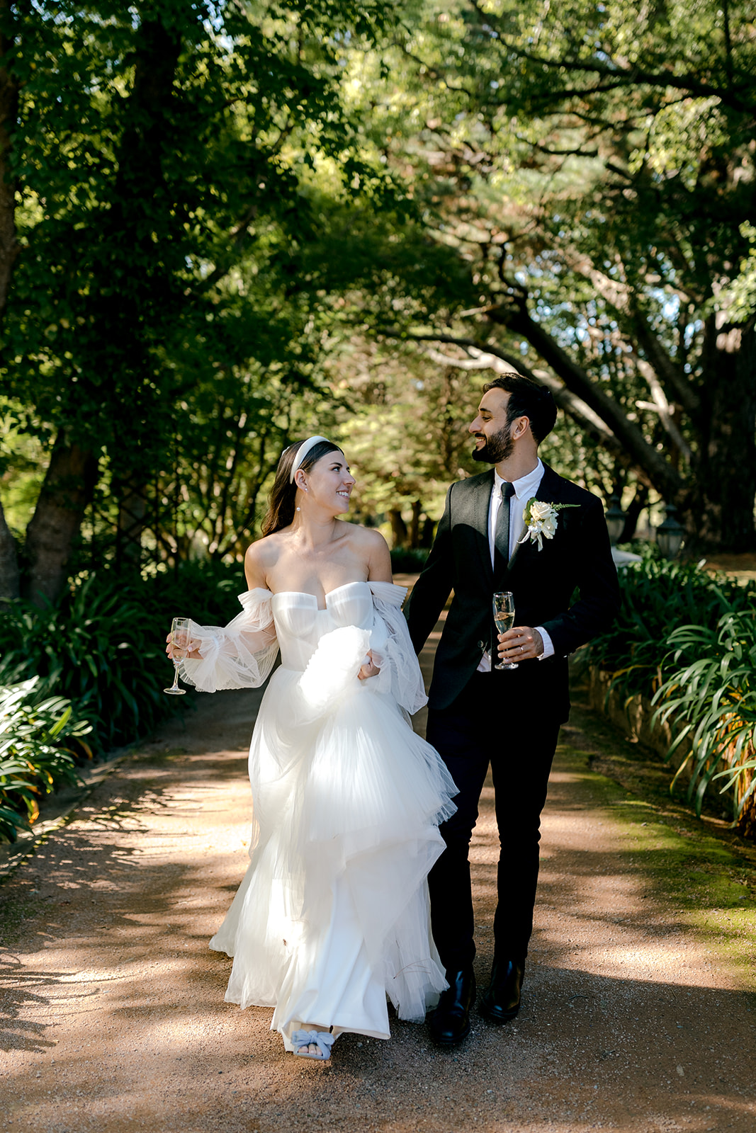 Portrait of bride & groom walking hand-in-hand in an English-inspired garden during their elegant country wedding.