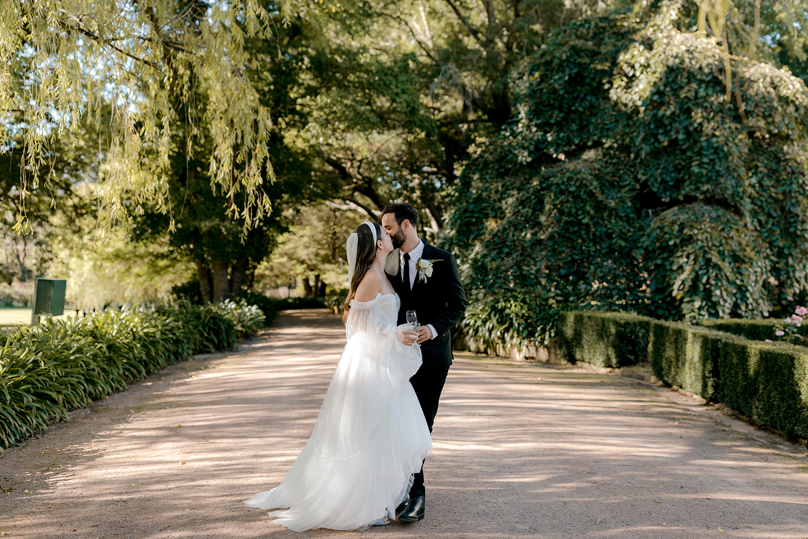 Portrait of bride & groom kissing in an English-inspired garden during their elegant country wedding.