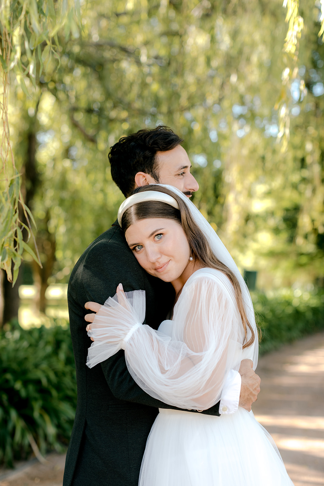 Intimate portrait of bride & groom hugging in an English-inspired garden during their elegant country wedding.