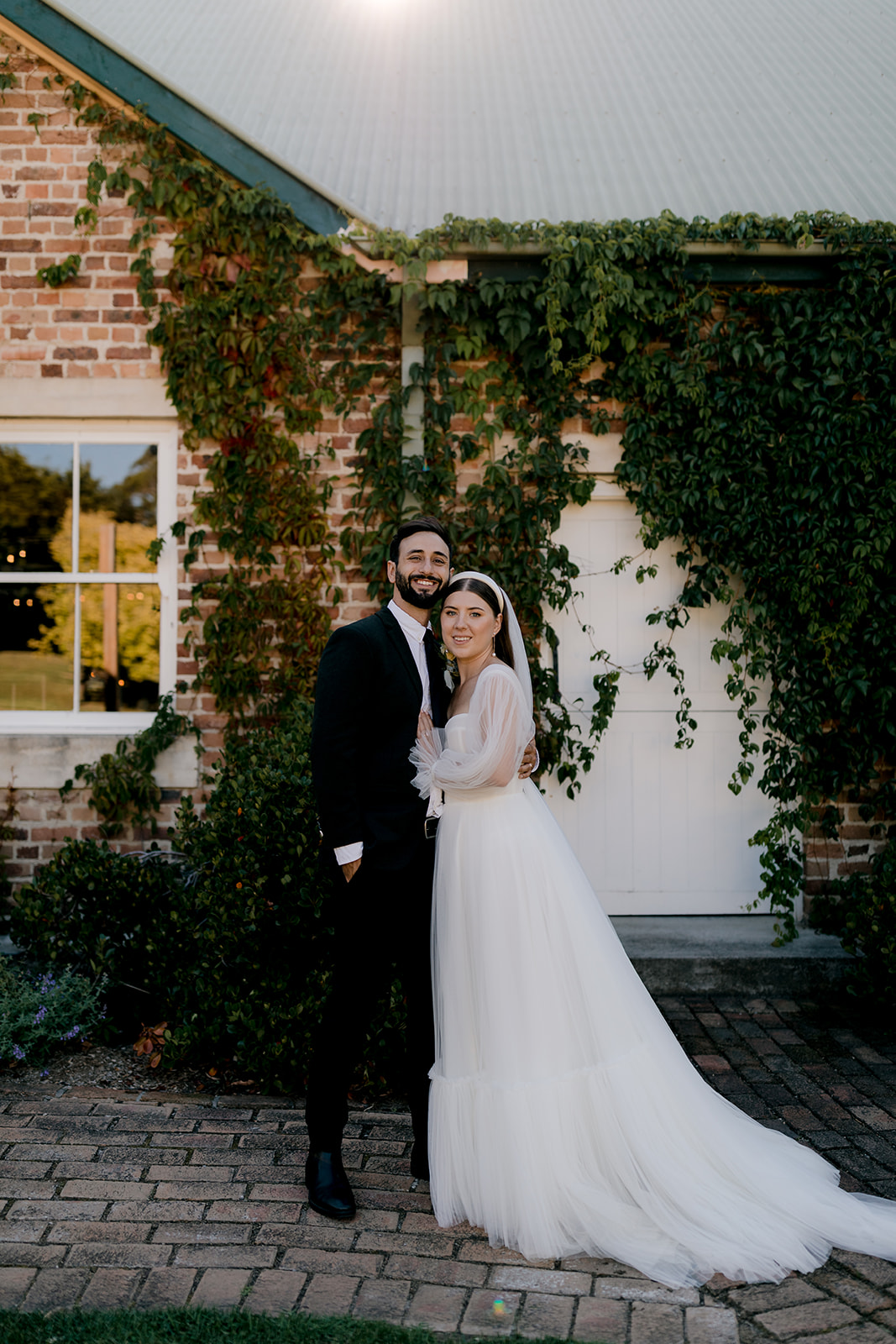Portrait of bride & groom in front of heritage venue at their elegant country wedding.