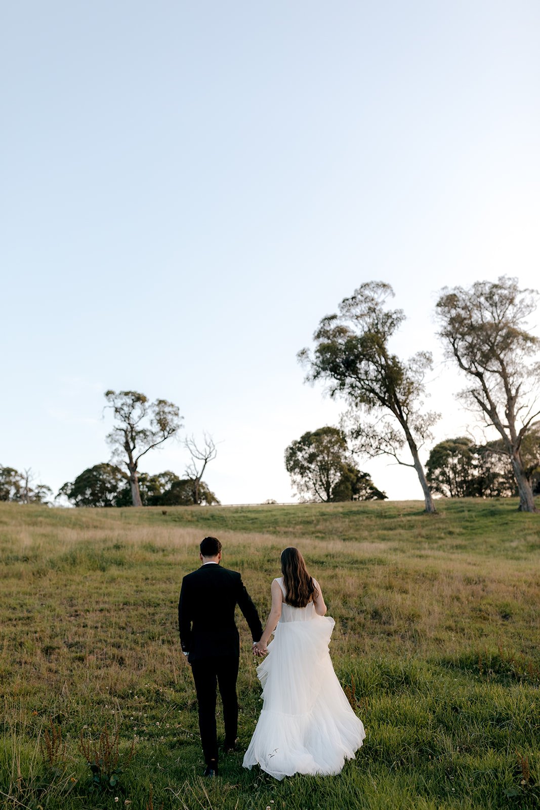 Bride & groom walking hand-in-hand at blue hour during their elegant country wedding.