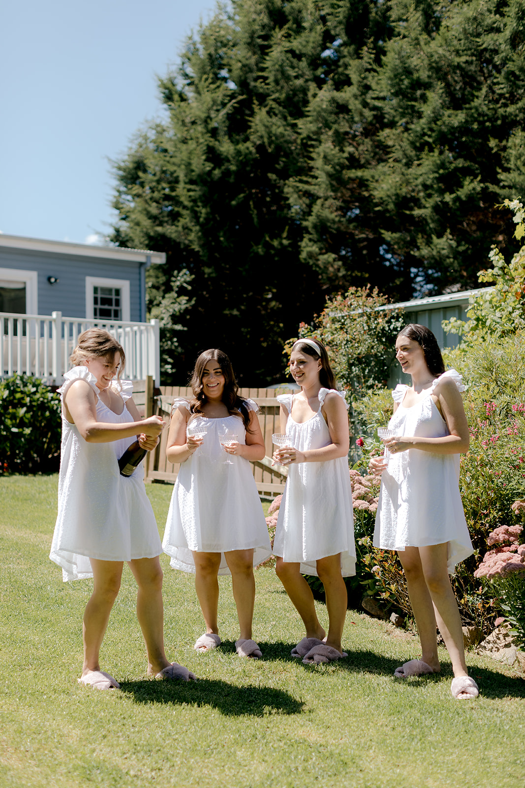 Bridesmaids popping champagne whilst getting ready for an elegant country wedding.
