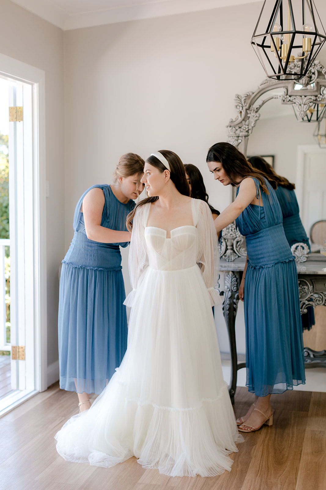 Bridesmaids helping bride get ready for her elegant country wedding.