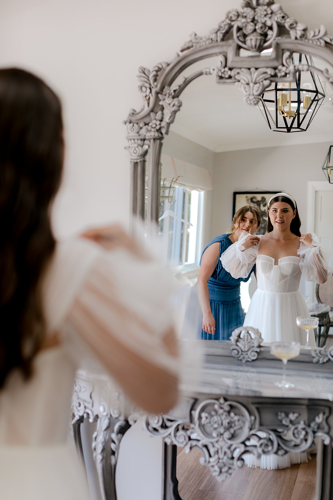 Bridesmaids helping bride get ready for her elegant country wedding.