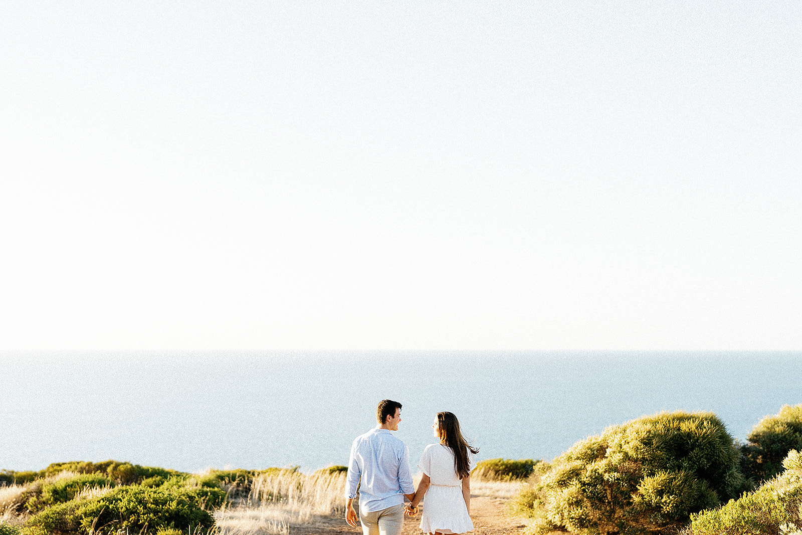 Young couple walking hand in hand, engagement photos in Australian Beach