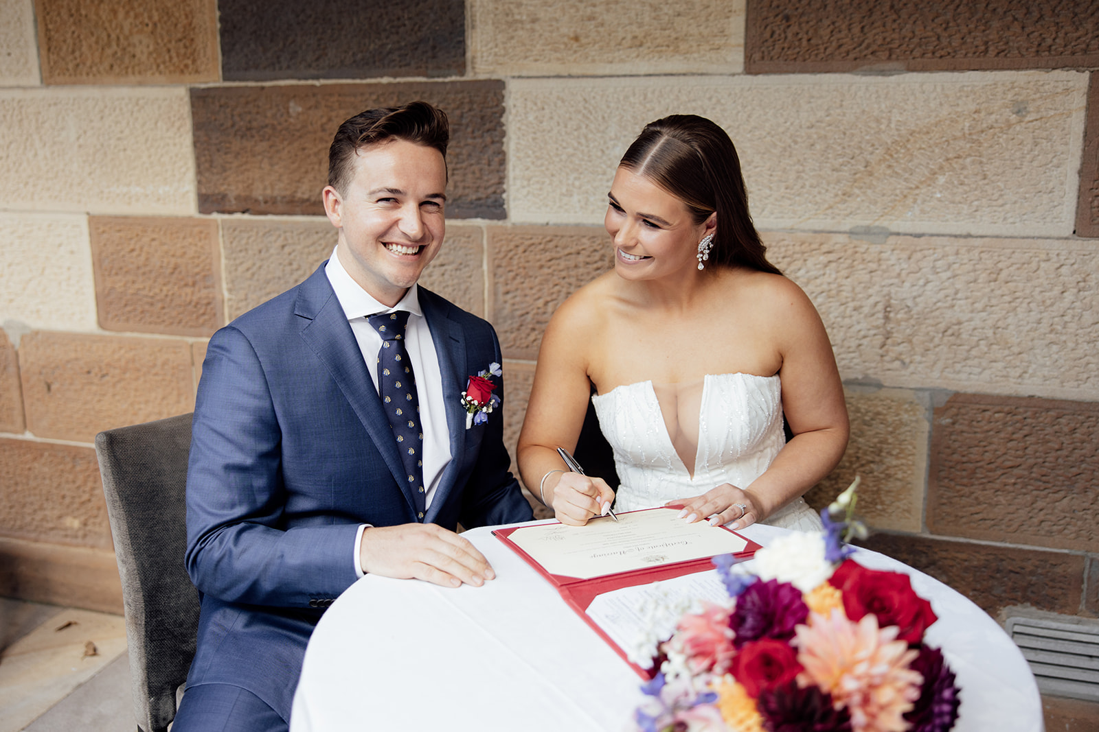 A bride and groom signing their marriage certificate.