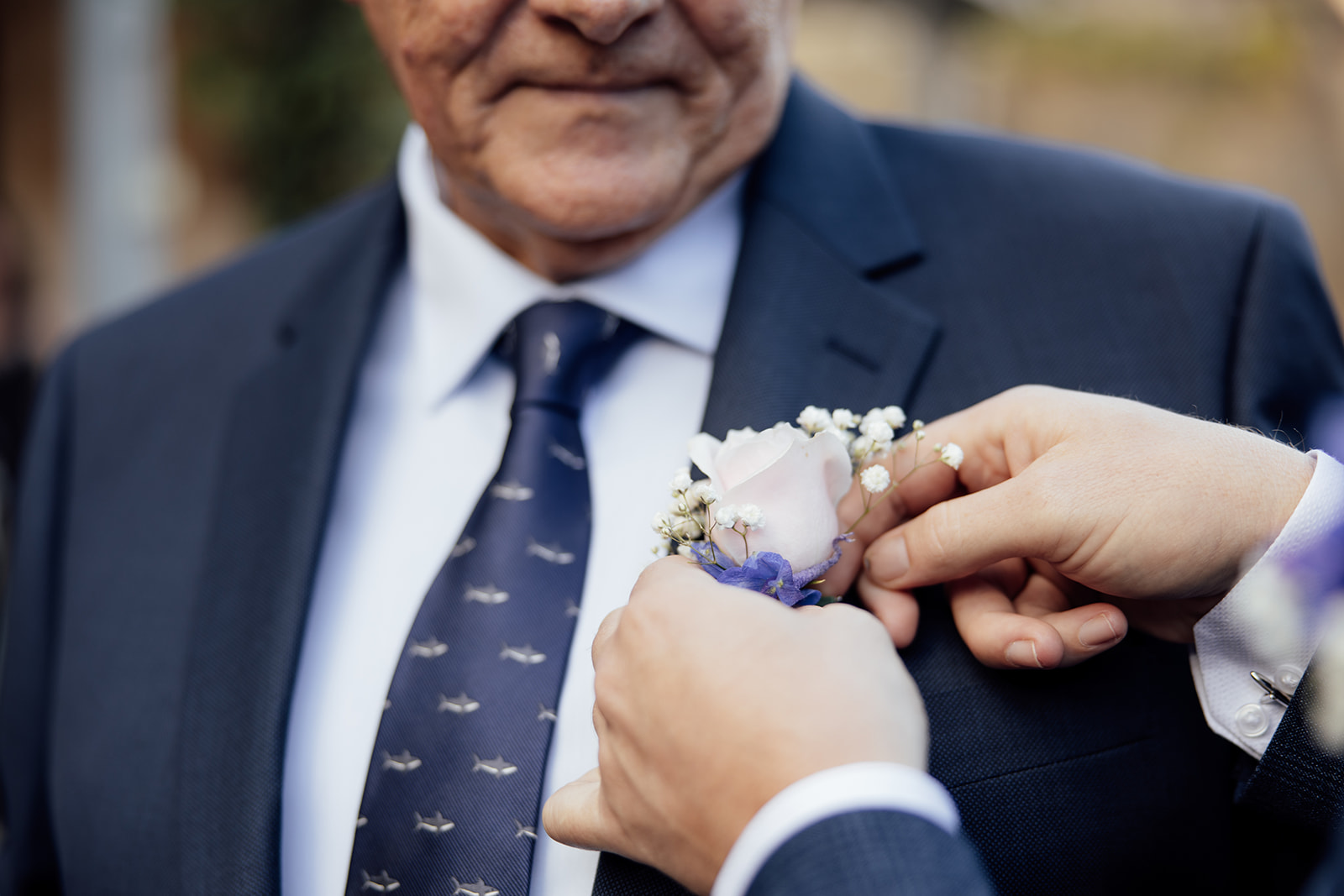 A man in a suit getting a boutonniere put on