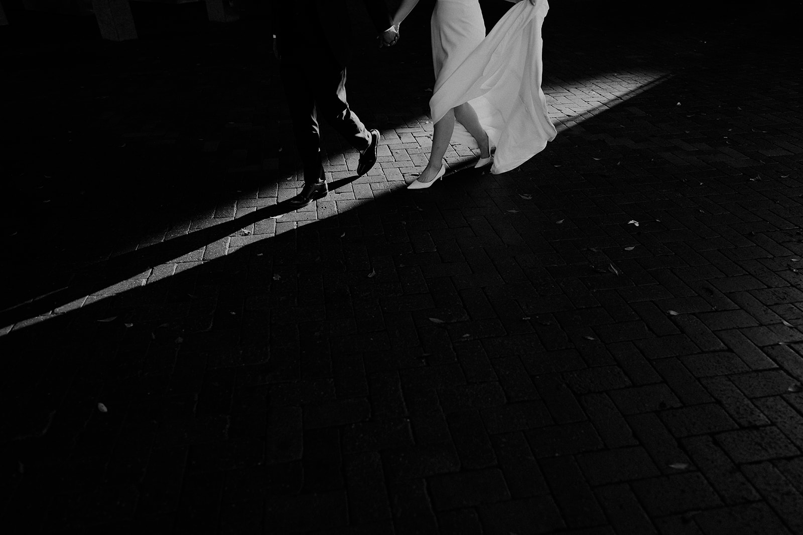 A black-and-white image of the bride and groom, walking away, showing only their feet in a very artistic manner
