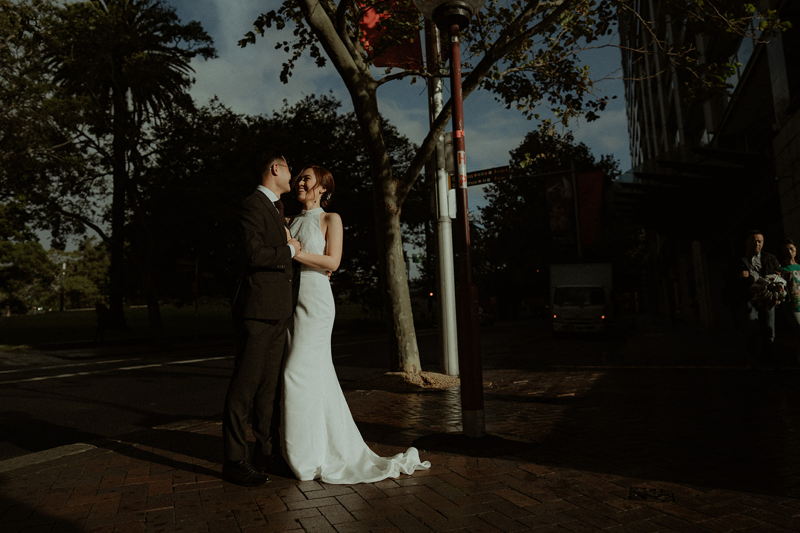 Bride and groom in harsh sunlight, creating a moody scene