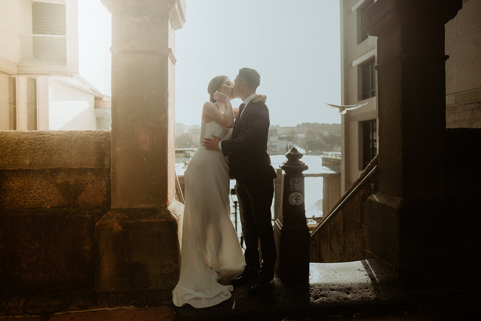 Bride and groom, kissing with the sunlight behind them in Sydney