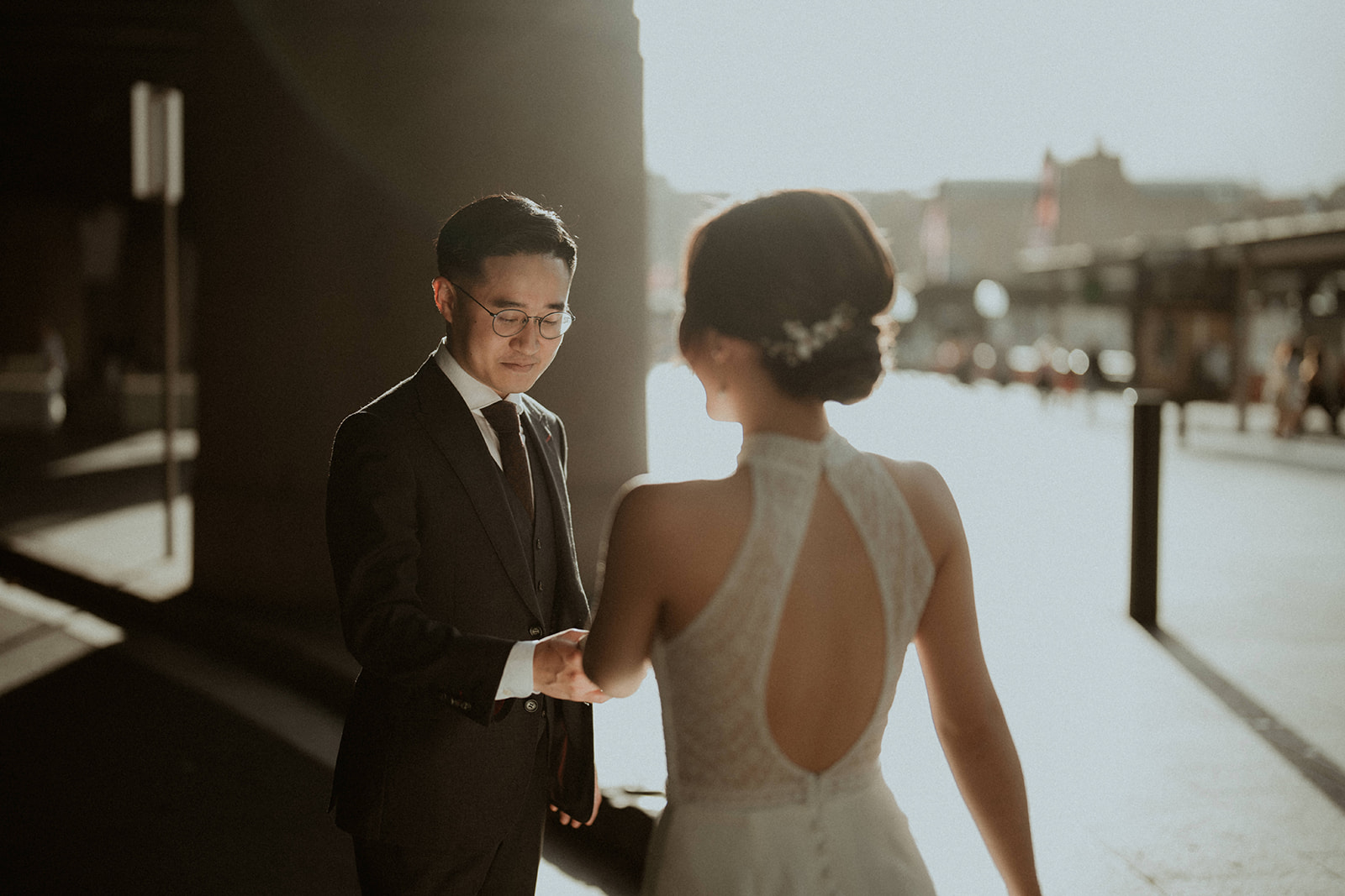 Groom, holding the bride's hand with the sun lit behind them