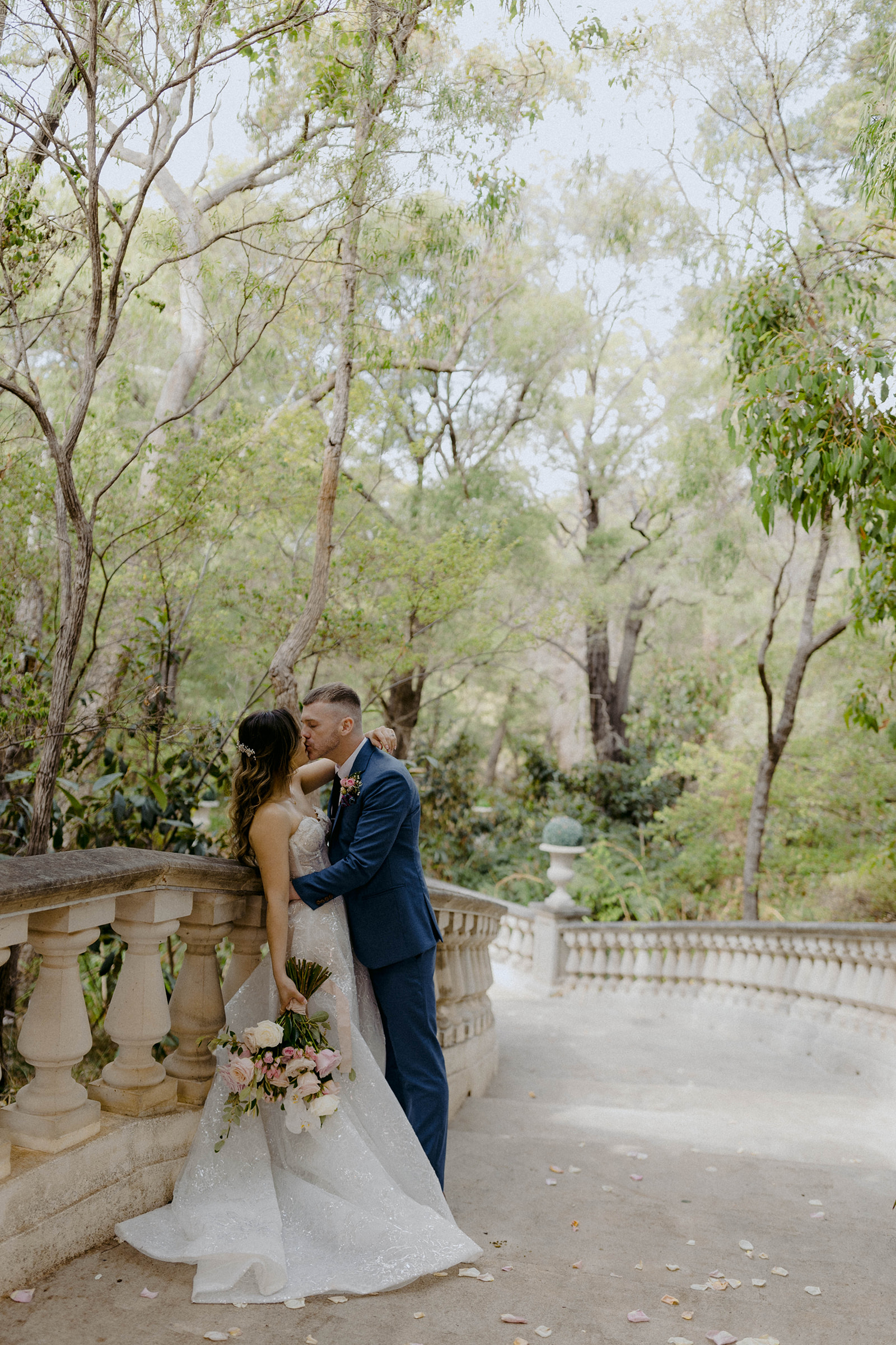 A couple who eloped at La Foret Enchantee in Margaret River kiss on stone steps. 