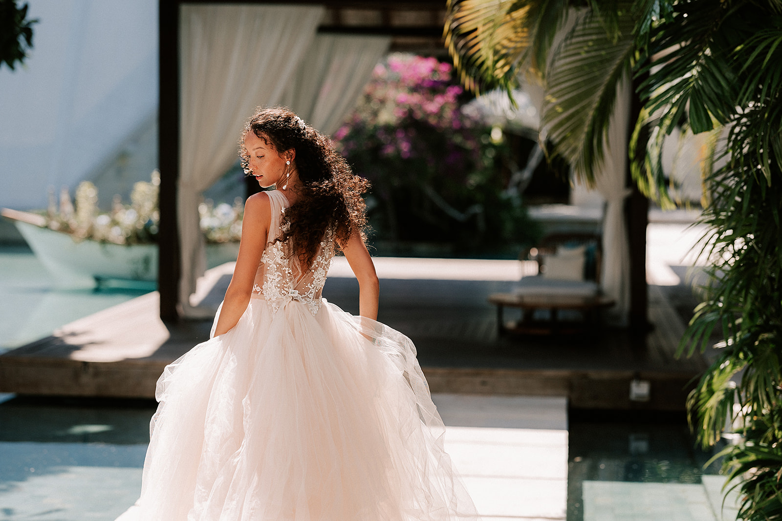 Bride is playfully walking away from the camera with the sun illuminating her gown