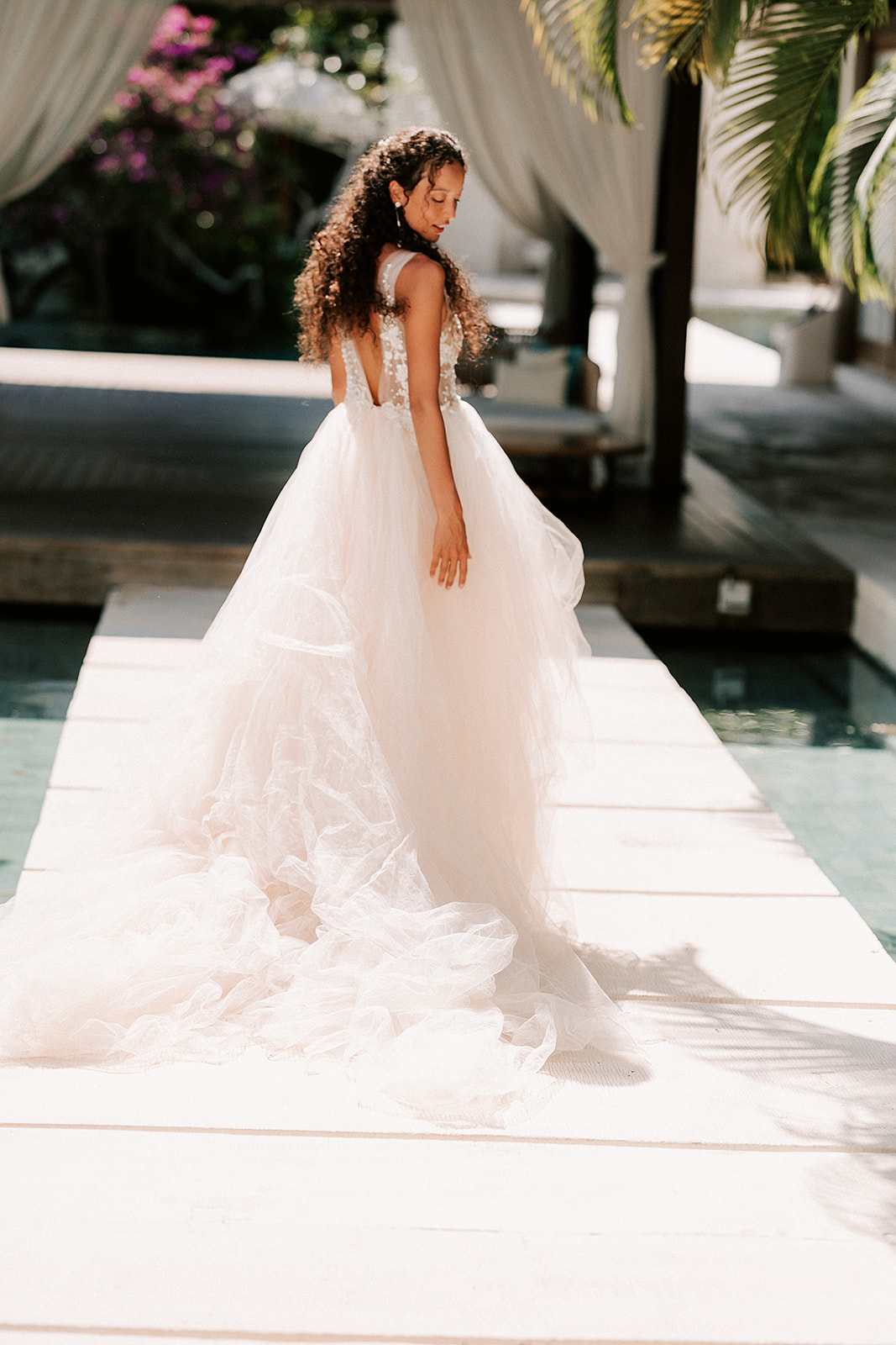 bride is walking down a white paved area next to a pool at luxury venue in Bali