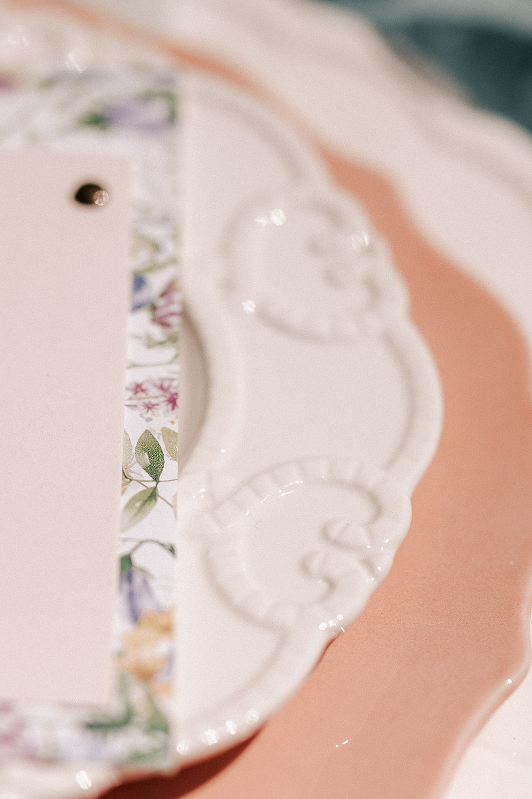 close up of scalloped plate, place card and peach coloured large plate setting