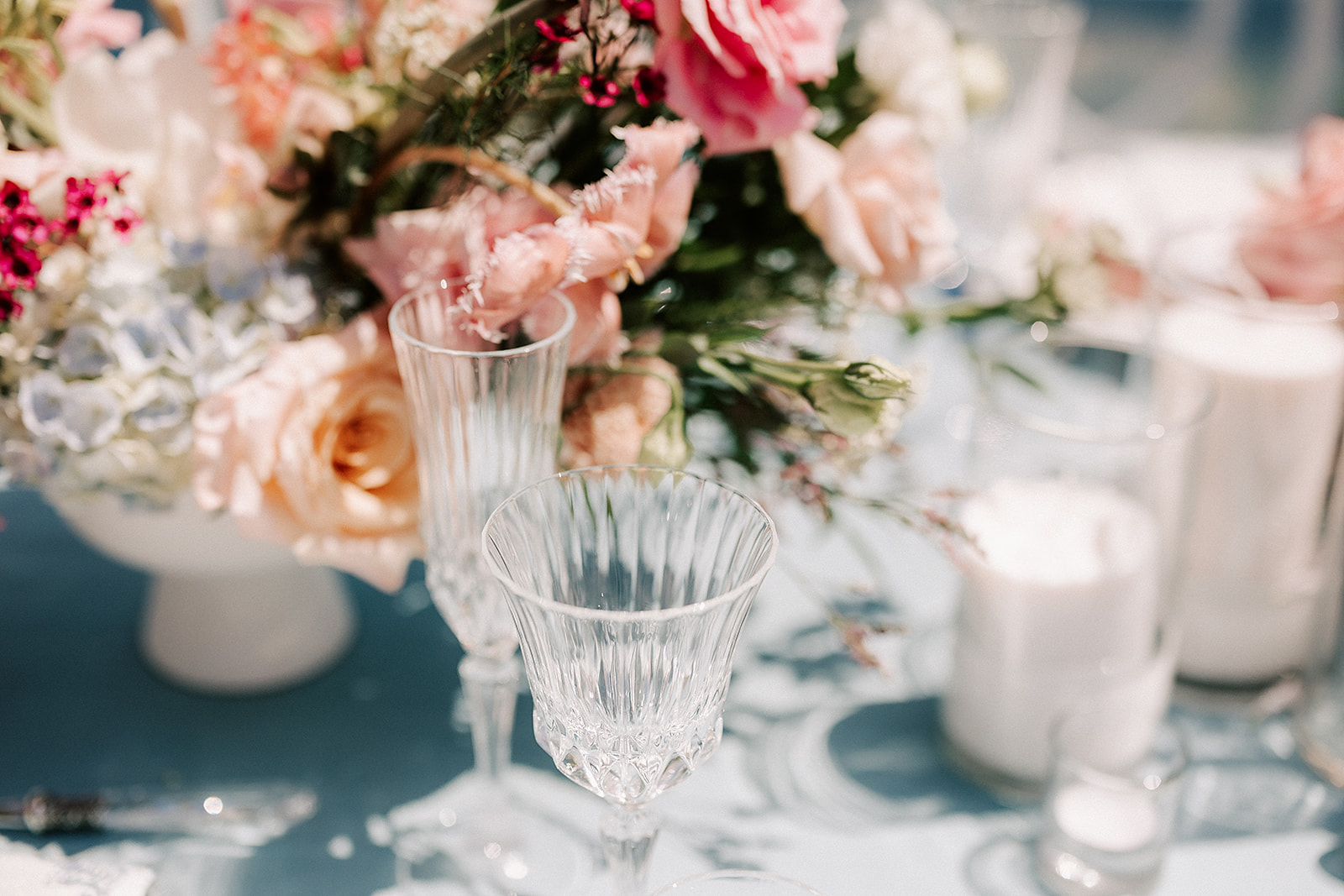 luxury wedding table settings, including crystal glassware and pink and white flowers