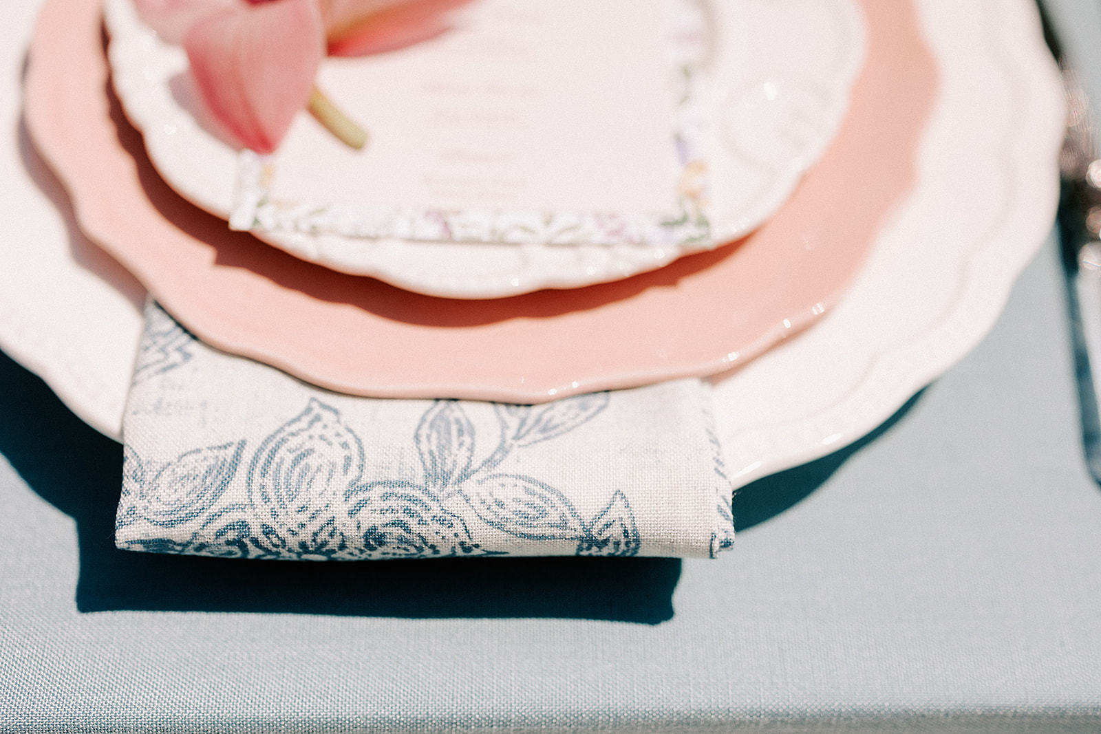 Wedding table place setting with floral blue napkin and pink  plate