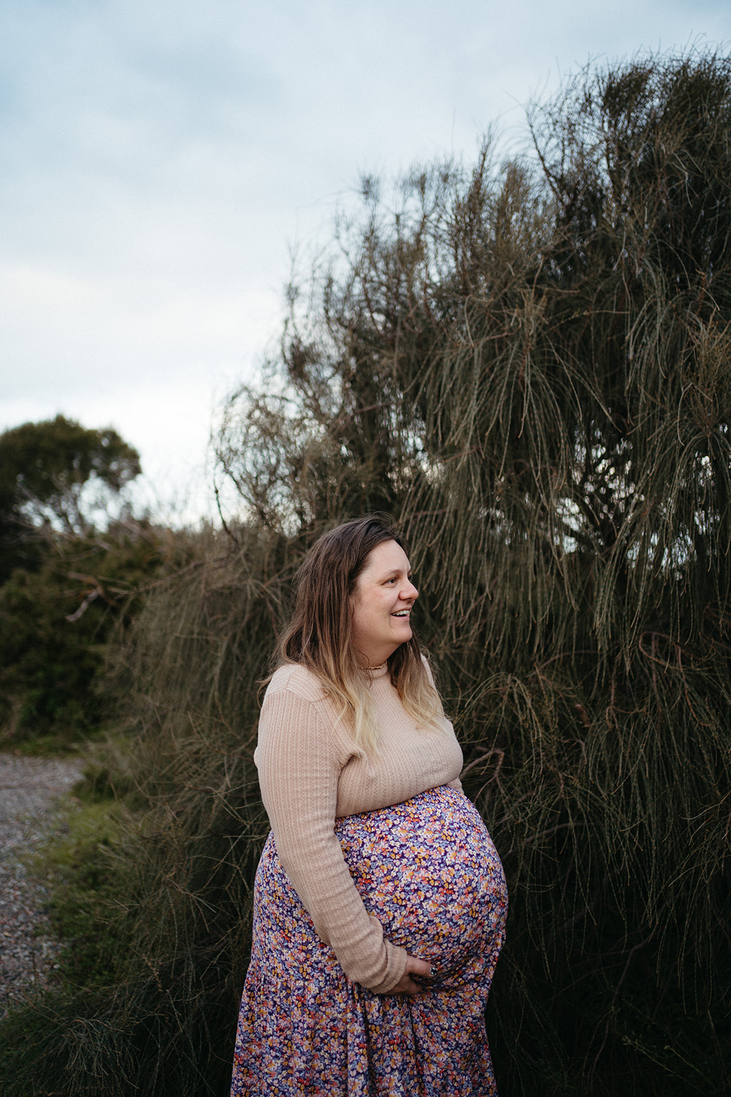 a profile of a pregnant woman who is wearing a pink floral skirt