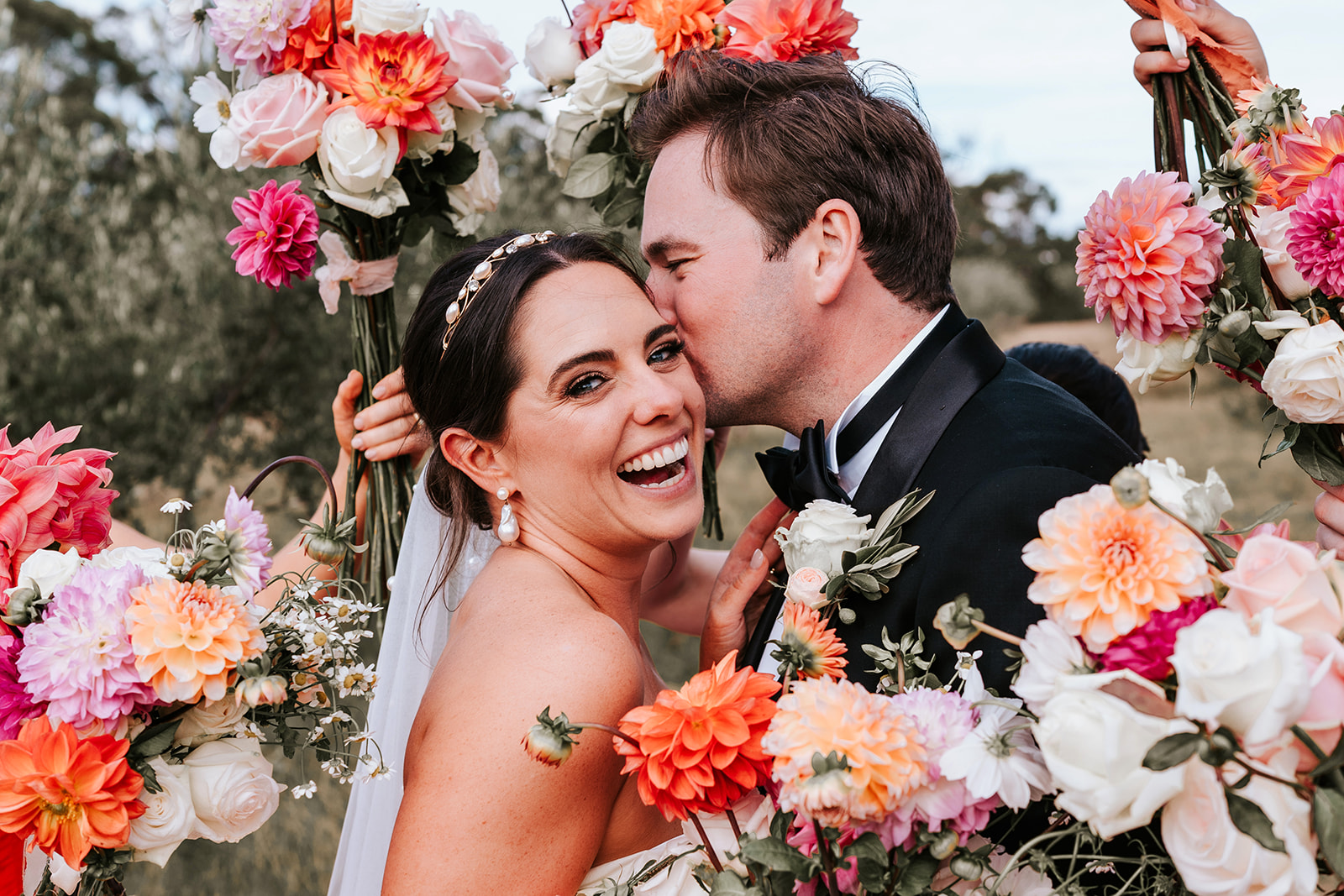 Bride & Groom kissing surrounded by flower bouquets