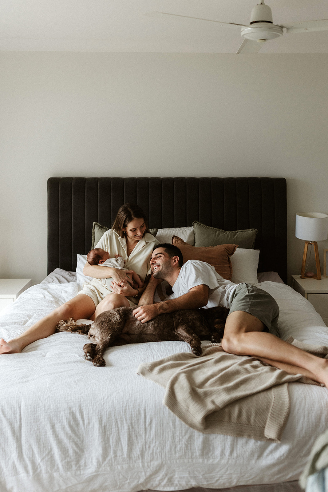 parents laying on bed with baby & dog