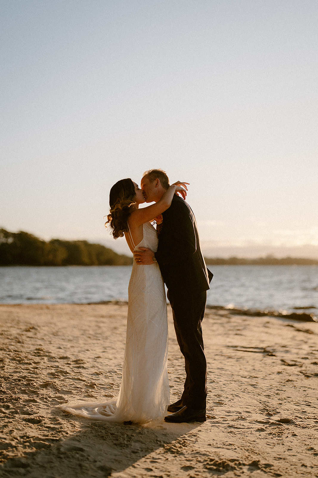 A newly wedded couple having a cuddle on the beach at their Worrowing Jervis Bay wedding.