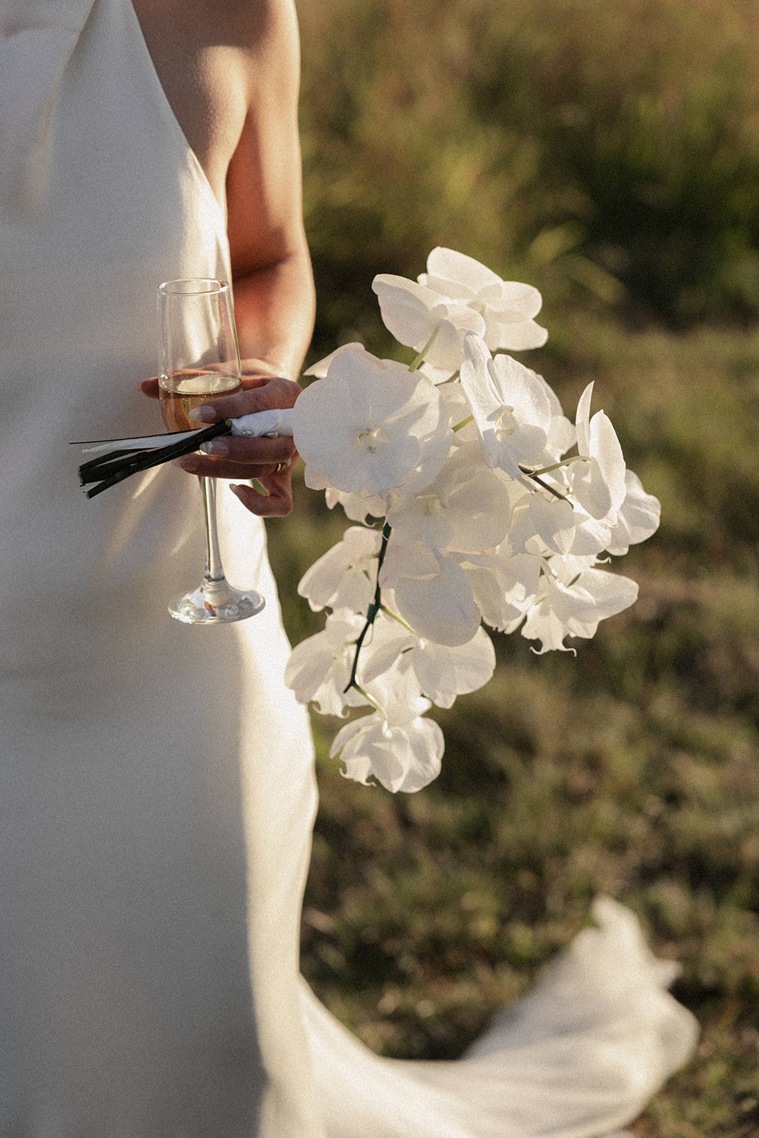 A bride with minimal and elegant chic style holding her bouquet of orchids